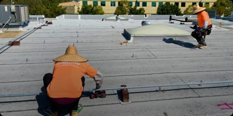 Cyberdyne employees wearing orange shirts diligently working together on a roof, showcasing their commitment to safety and craftsmanship.