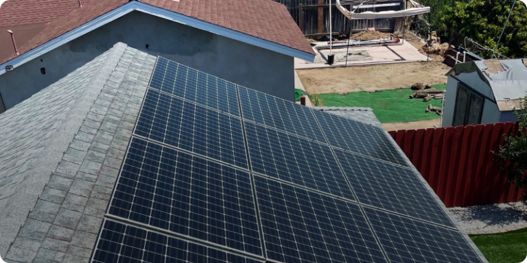 A rooftop solar panel installed on a house in San Diego, surrounded by a green backyard, harnessing solar energy for sustainable living.